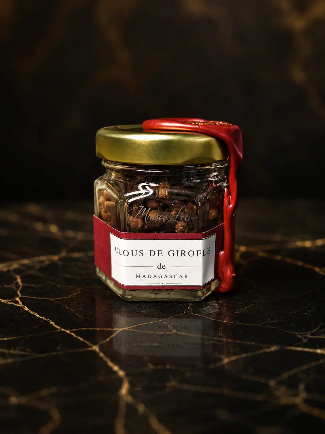 Pot en verre de Clous de Girofle de Madagascar du Pack Découverte Sélection Intense Maison Loïs, épices premium scellées de cire rouge sur marbre noir.