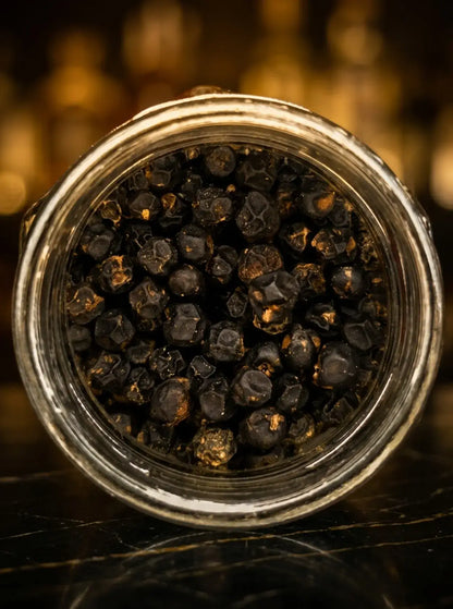 Poivre noir de Madagascar en grains entiers, présenté en gros plan pour la gastronomie et la cuisine d’exception.